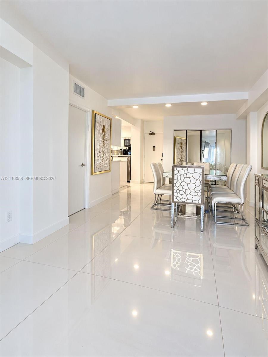 Large-format polished tile flooring, recessed ceiling lighting, and mirrored wall accents