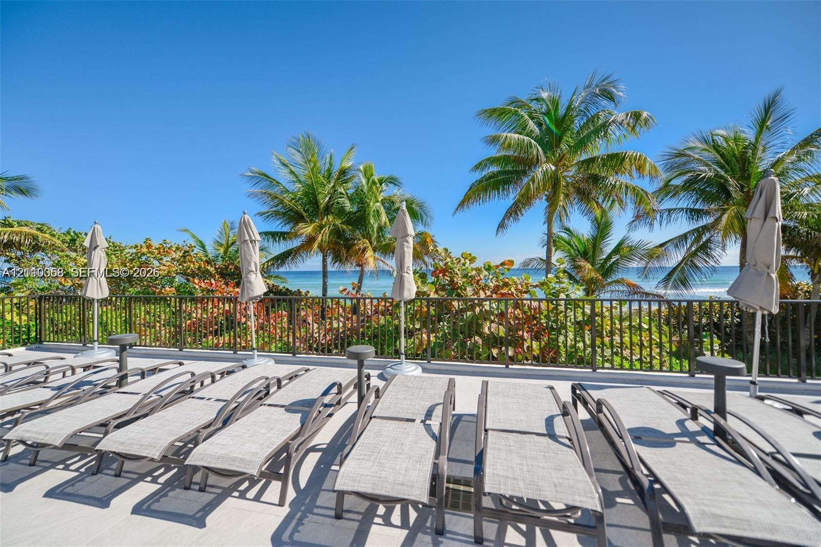 Outdoor terrace featuring a concrete deck, metal perimeter railing, and mature palm trees