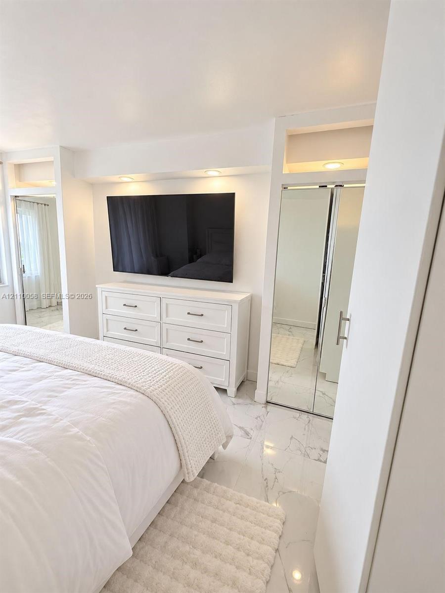 Stone-finish flooring, mirrored closet doors, and recessed ceiling lighting