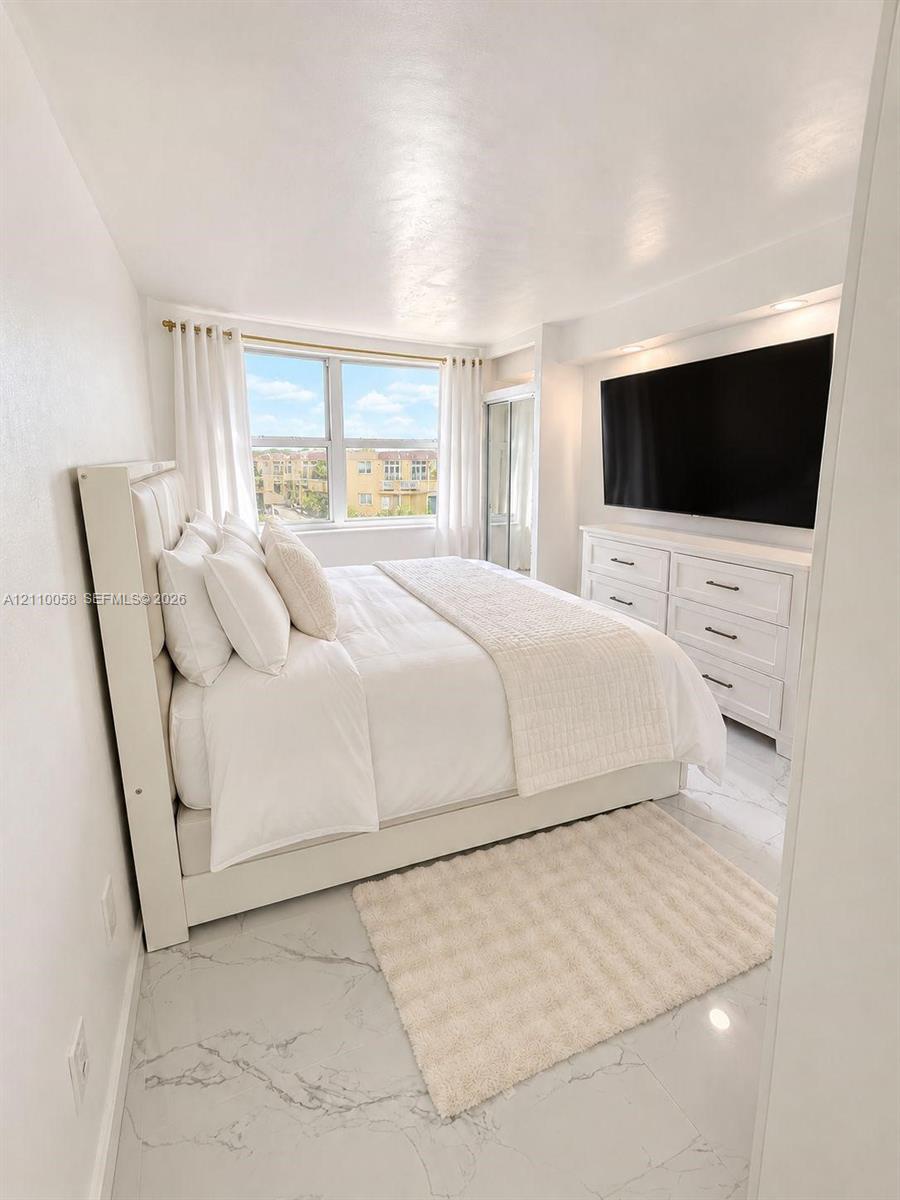 Neutral-toned room featuring large-format stone-finish flooring, recessed lighting, and a window with exterior exposure