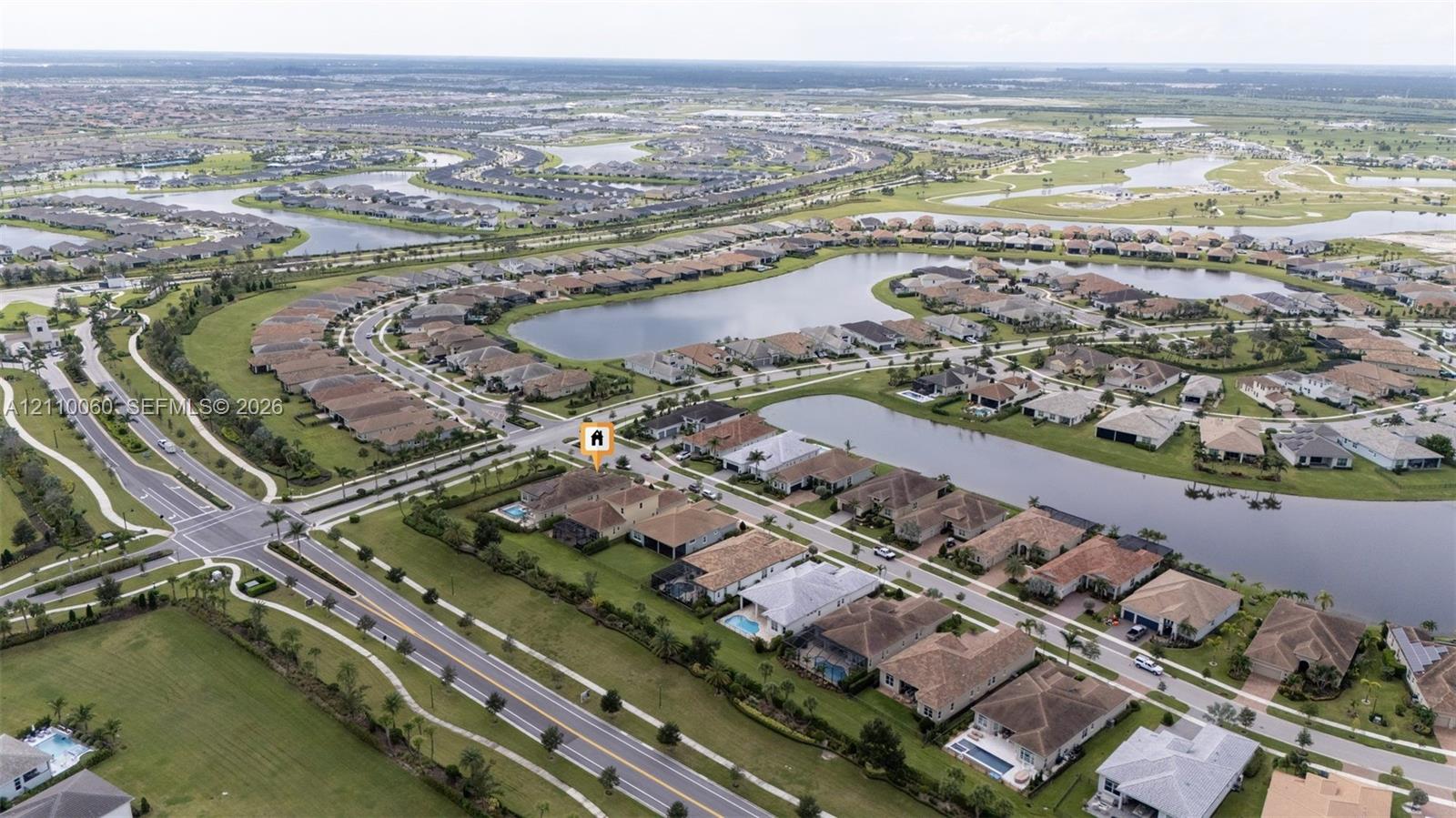 Aerial perspective featuring a tile-roofed residence situated within a planned community with waterfront lots and extensive manicured landscaping