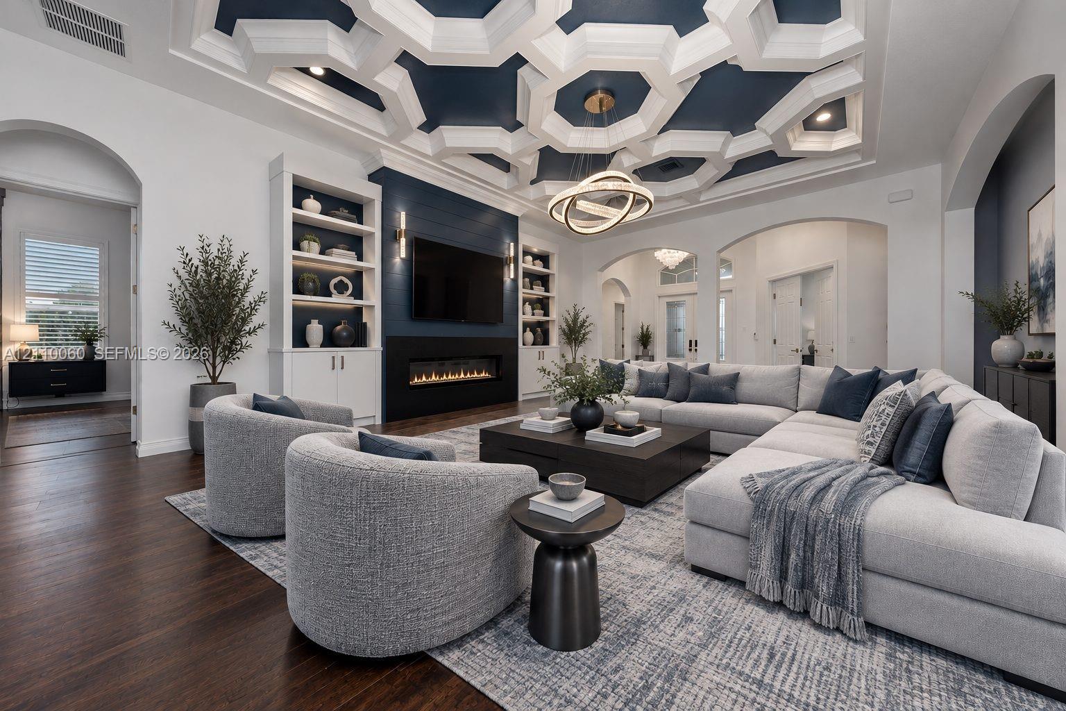Virtually staged. Living area featuring an intricate geometric coffered ceiling, linear fireplace with a shiplap surround, built-in shelving, hardwood flooring, and arched doorways