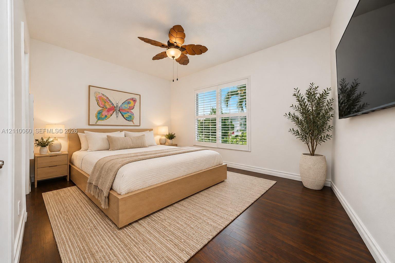 Virtually staged. Dark wood-finish flooring, plantation shutters, and a multi-blade ceiling fan with an integrated light fixture