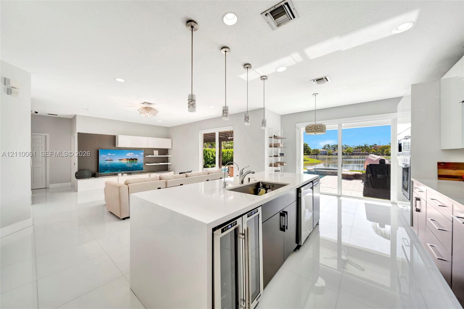 Kitchen featuring a waterfall-edge stone countertop, custom cabinetry, built-in dual wine refrigeration, recessed ceiling lighting, and large sliding glass doors