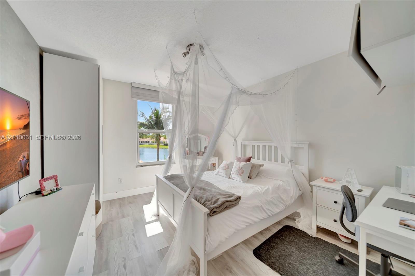 Light-filled room featuring wood-finish flooring, a neutral color palette, and a window overlooking a water feature