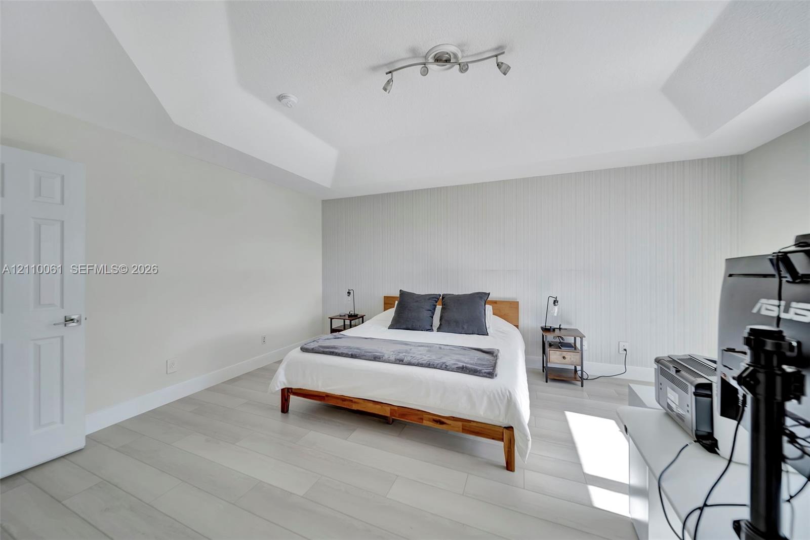 Tray ceiling, vertical paneling accent wall, and wood-finish flooring