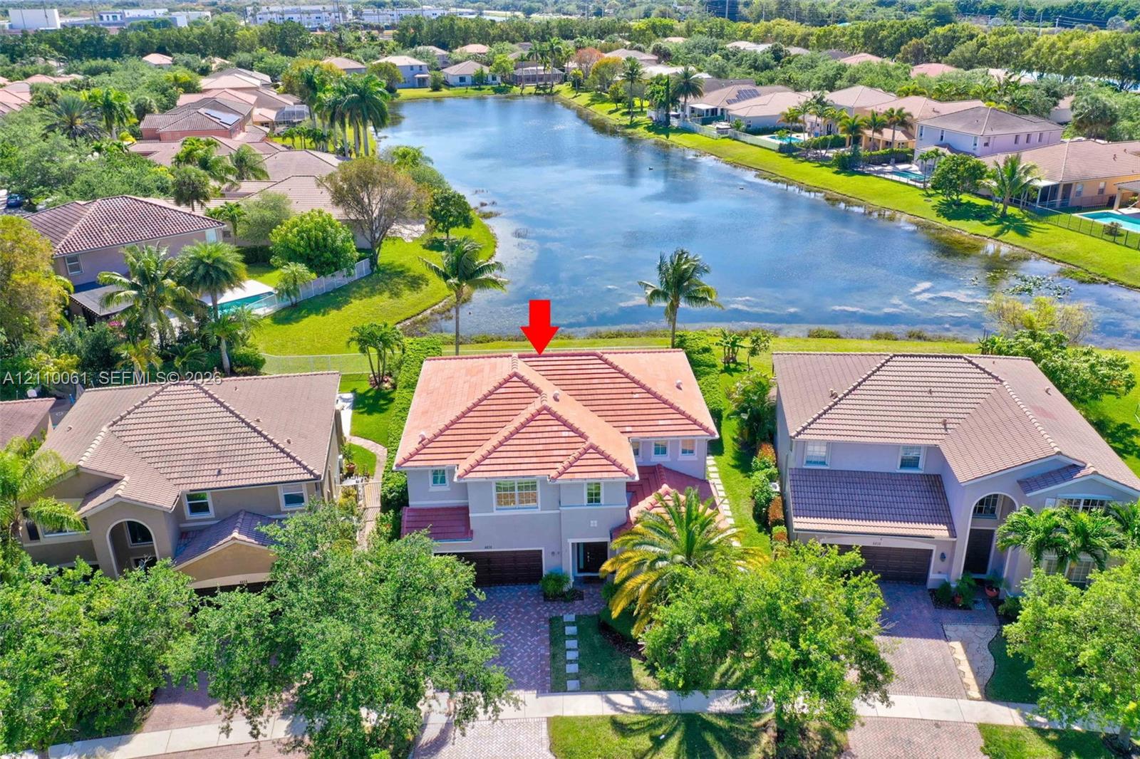 Two-story residence featuring a tile roof, paver driveway, and direct water frontage on a lake