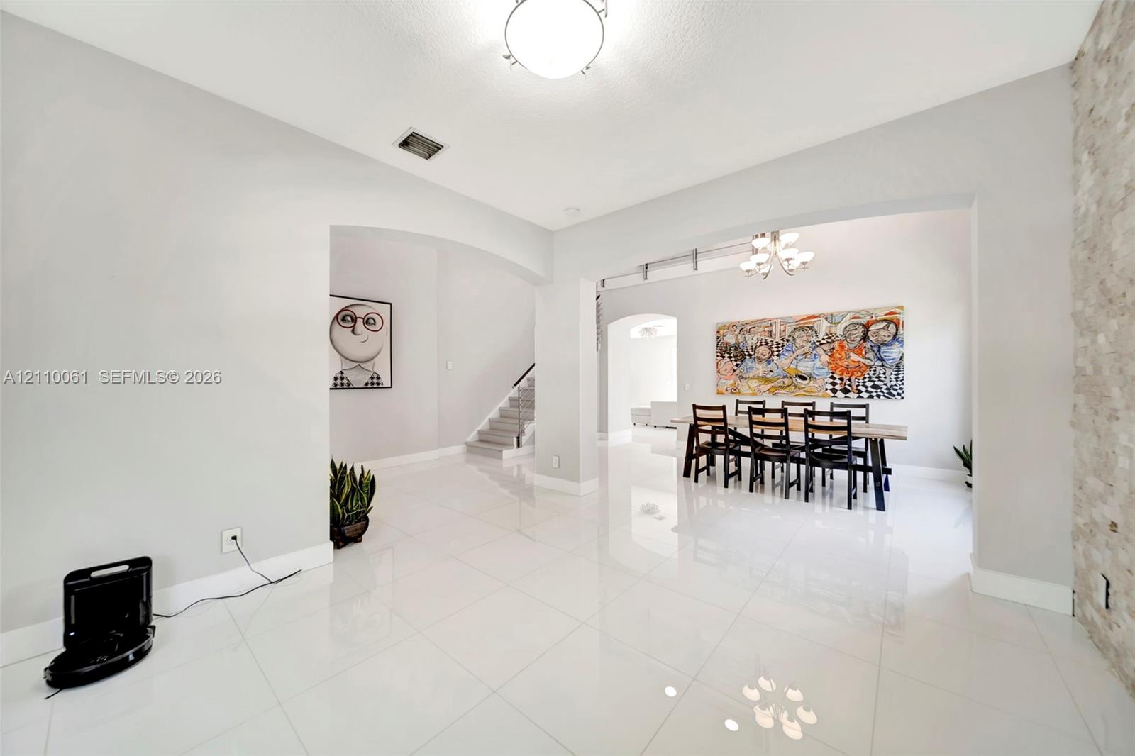 Polished tile flooring, neutral wall tones, arched entryways, decorative stone-veneer wall accent, and overhead chandelier lighting