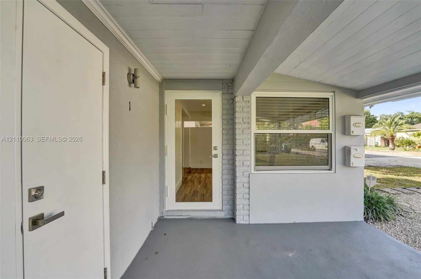 Covered entryway featuring a glass-panel entry door, brick exterior accents, dual wall-mounted mailboxes, and an external light fixture Covered entryway featuring a glass-panel entry door, brick exterior accents, dual wall-mounted mailboxes, and an external light fixture