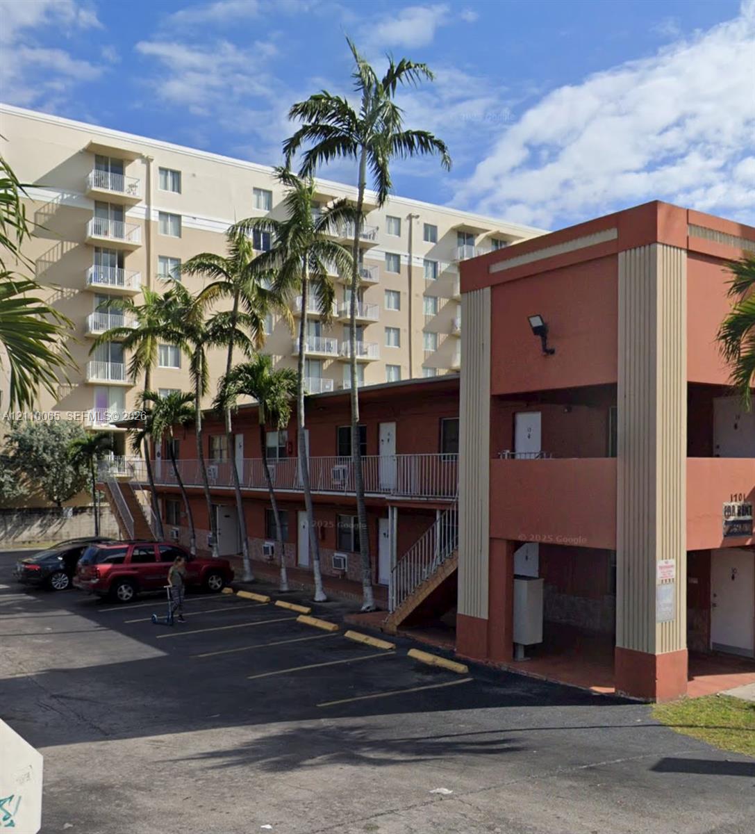 Two-story exterior with stucco finish, integrated outdoor staircase, metal railings, and dedicated asphalt parking