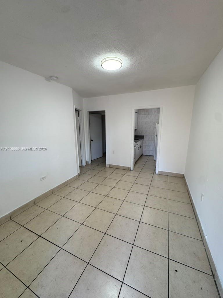 Interior space featuring large-format neutral tile flooring, smooth wall finishes, and a central flush-mount ceiling light fixture