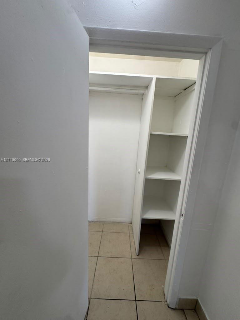 Storage area featuring tile flooring, built-in shelving, and a hanging rod