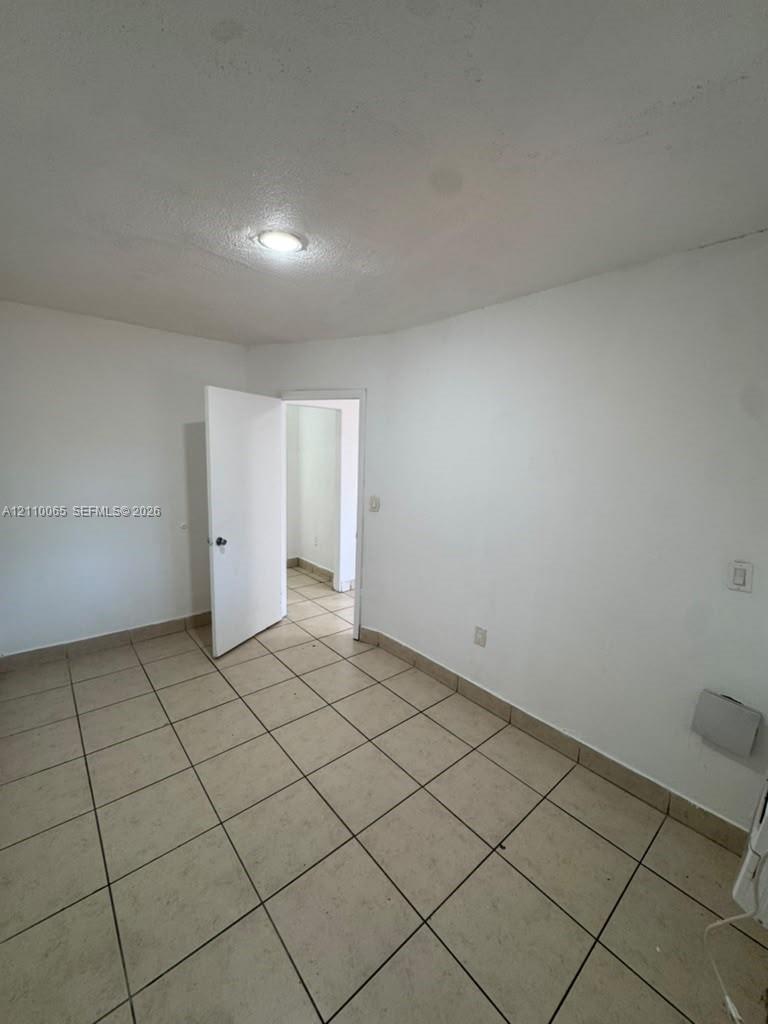 Neutral-toned tile flooring, white interior walls, and a recessed ceiling lighting fixture