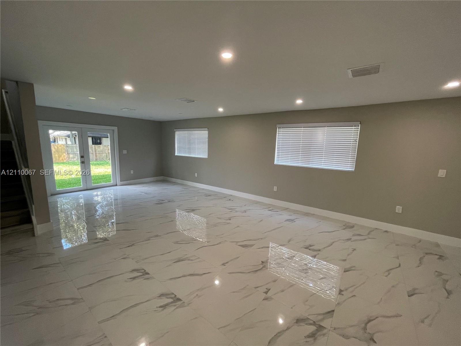 Kitchen featuring high-gloss white cabinetry, stone-finish countertops, stainless steel appliances, a double-basin undermount sink, and tile flooring with a veined pattern