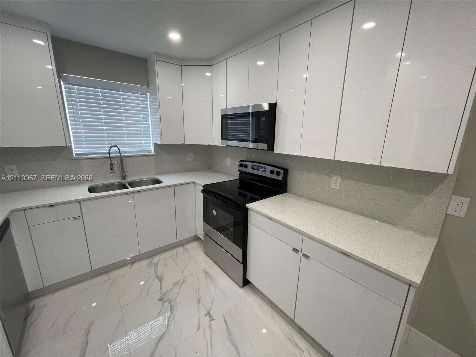 Kitchen featuring high-gloss white cabinetry, white stone-finish countertops, large-format tile flooring, stainless steel side-by-side refrigerator, and recessed ceiling lighting