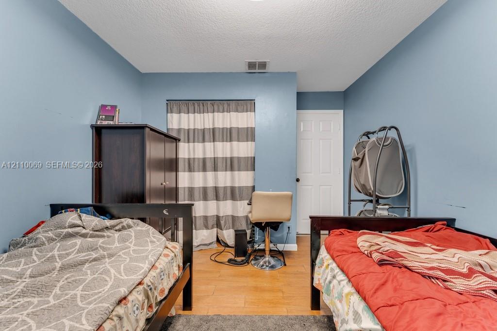 Room featuring wood-finish flooring, a six-panel interior door, and a built-in closet with sliding curtain closure