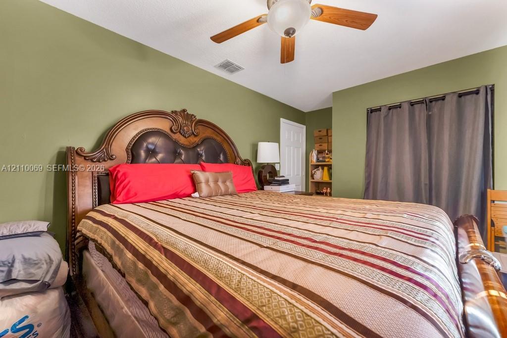 Bedroom featuring a multi-blade ceiling fan with an integrated light fixture and a multi-panel interior door