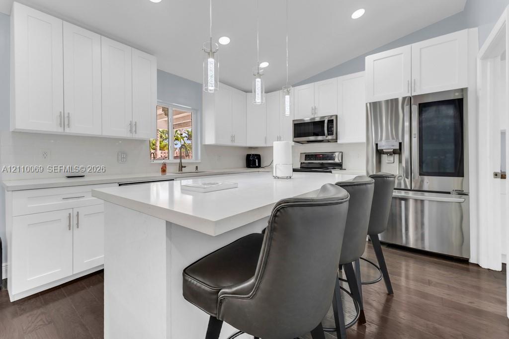 Kitchen featuring white cabinetry, quartz countertops, a central island, recessed lighting, and stainless steel appliances