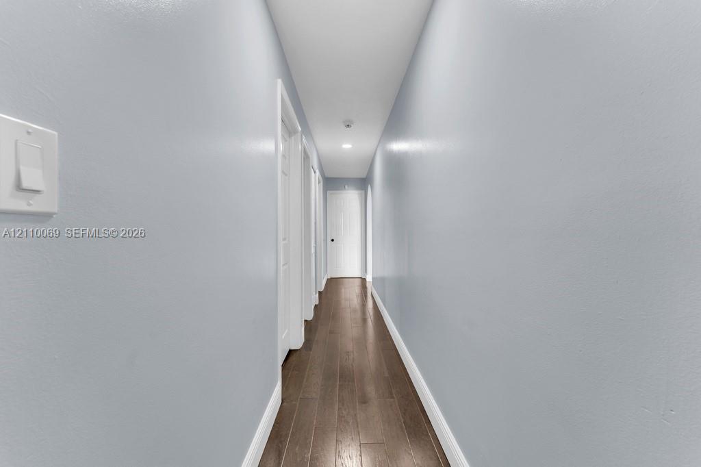 Hallway featuring wood-finish flooring, recessed lighting, and multiple interior paneled doors