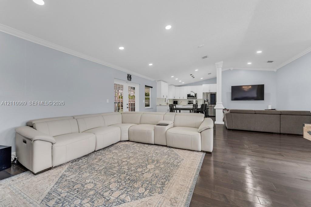 Open-concept interior featuring wood-finish flooring, recessed lighting, vaulted ceilings, and a structural column