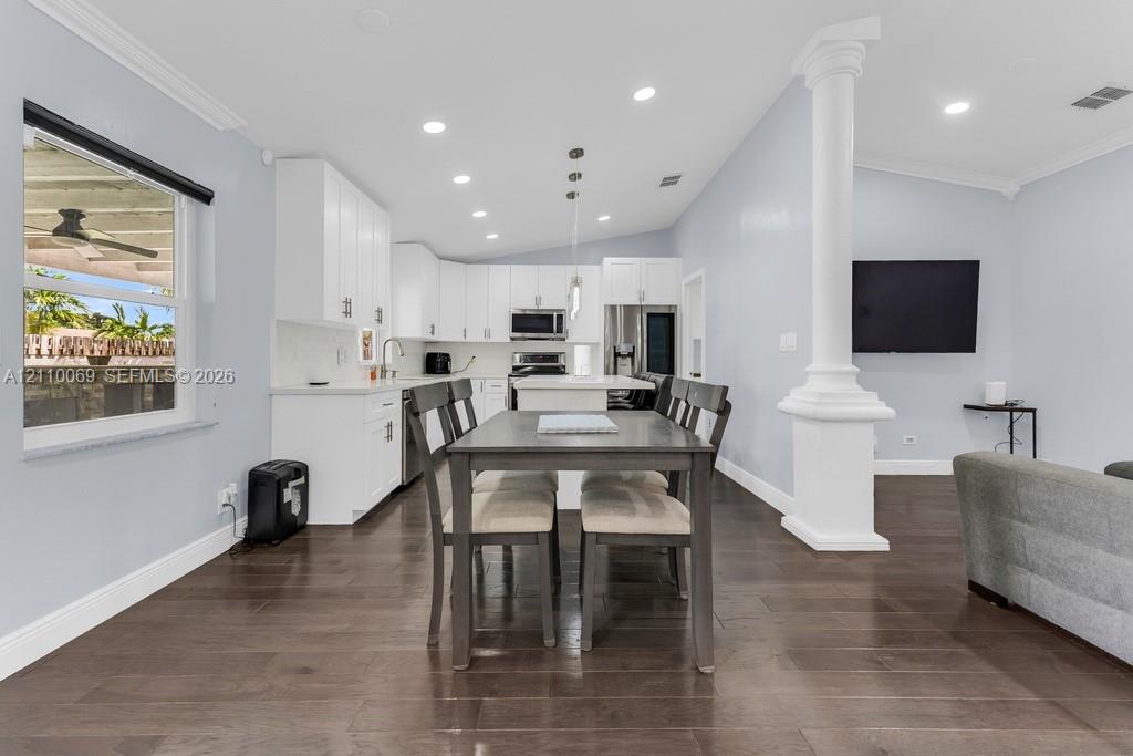 Open-concept kitchen featuring white shaker-style cabinetry, quartz countertops, a central island, recessed lighting, and dark wood-finish flooring
