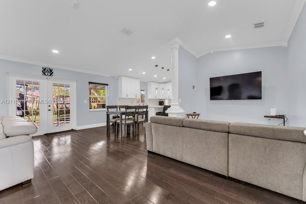 Interior space featuring wood-finish flooring, recessed lighting, a structural column, crown molding, and glass-paneled double doors