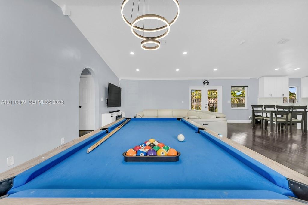 Open-concept interior featuring recessed lighting, modern tiered ring chandelier, dark wood-finish flooring, and glass-paned double doors
