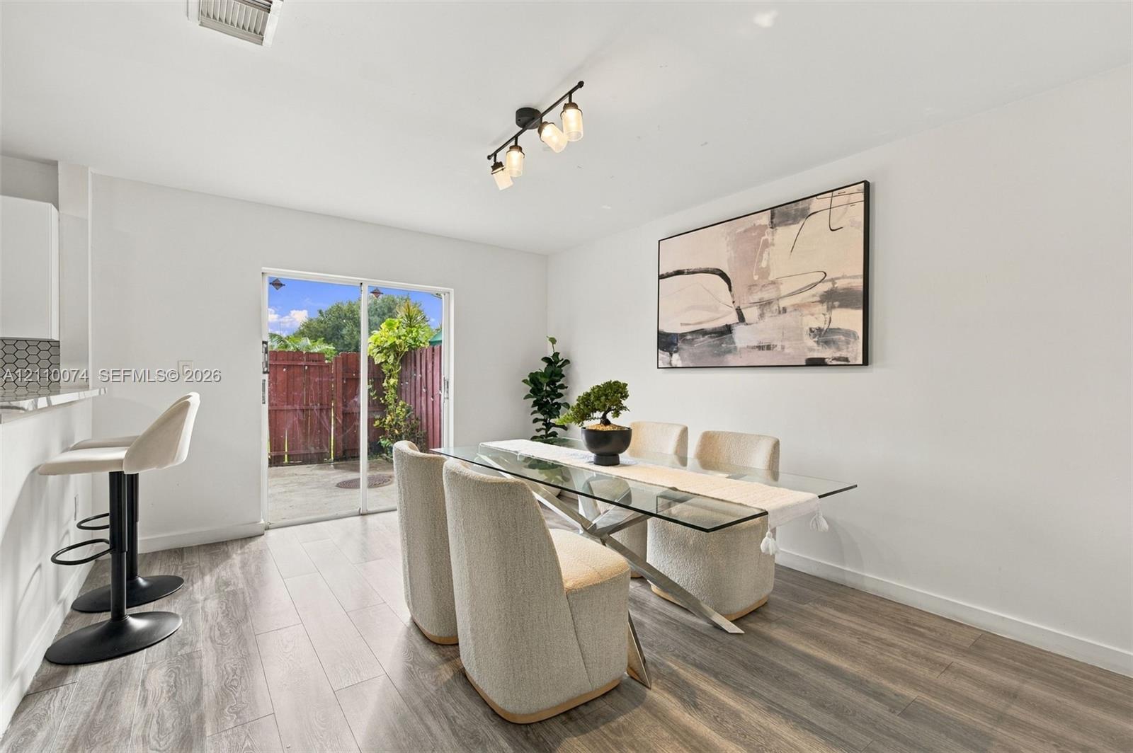 Dining area featuring wood-finish flooring, a multi-bulb ceiling fixture, a breakfast bar, and sliding glass doors with exterior access