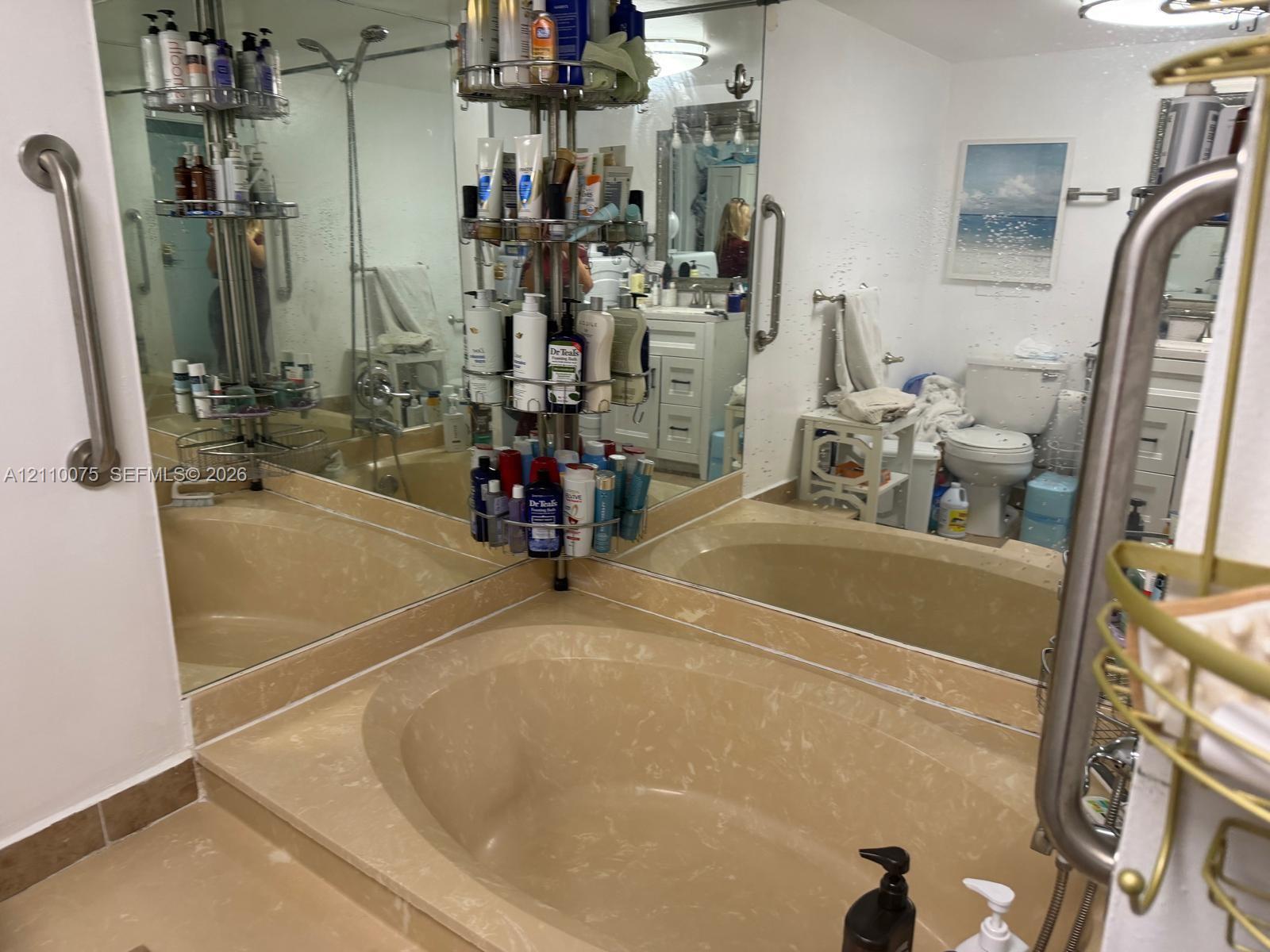 Built-in soaking tub with surround, wall-to-wall mirrors, and stainless steel grab bars