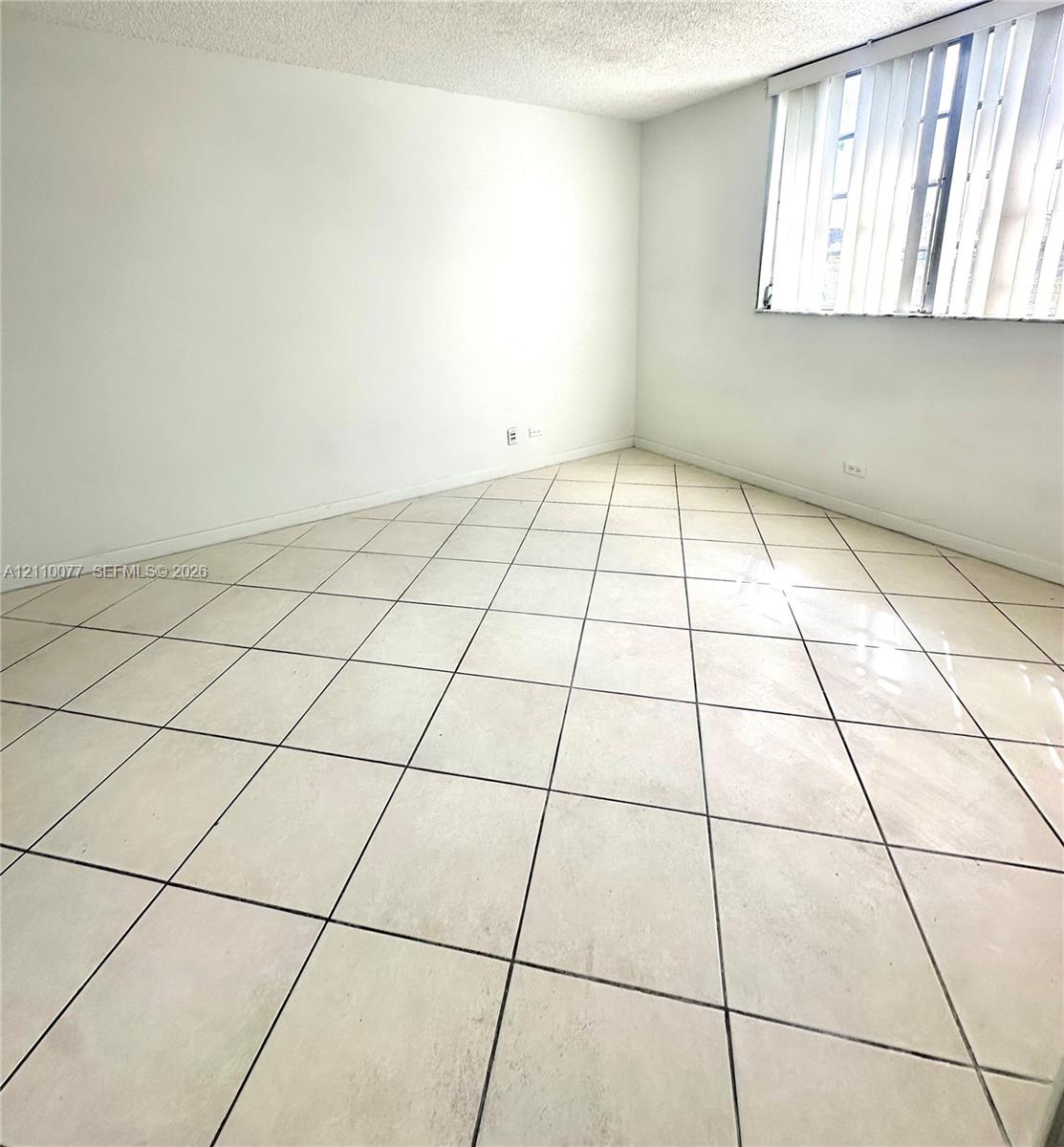 Interior space featuring diagonal ceramic tile flooring, textured ceilings, and window blinds