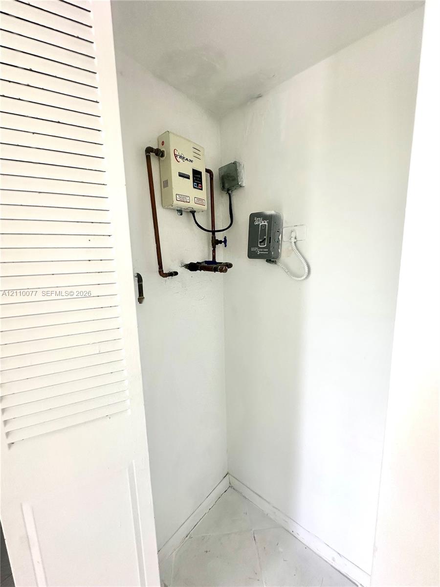Tankless water heating system with copper piping and hard-wired electrical control unit, housed within a louvered closet