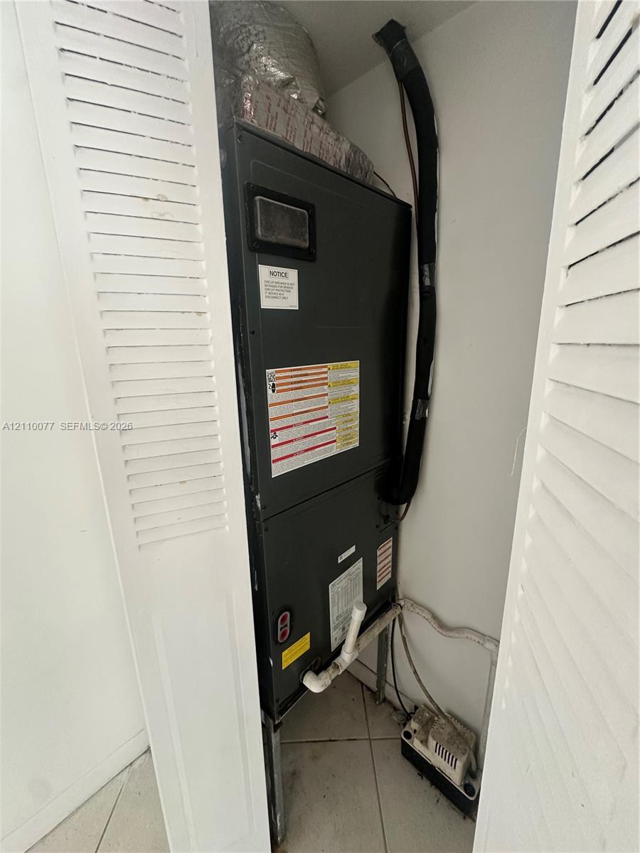 Vertical heating and cooling unit housed in a closet with white louvered doors