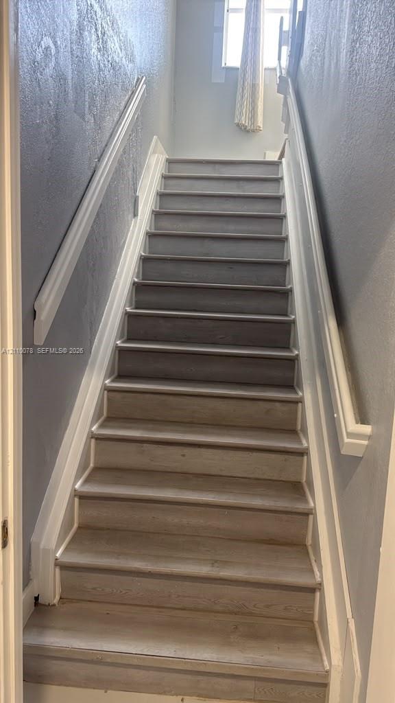 Staircase featuring wood-finish treads and white painted handrails