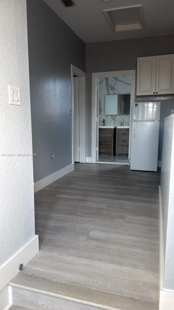 Wood-finish flooring, upper cabinetry, and solid surface bathroom vanity with dual sinks