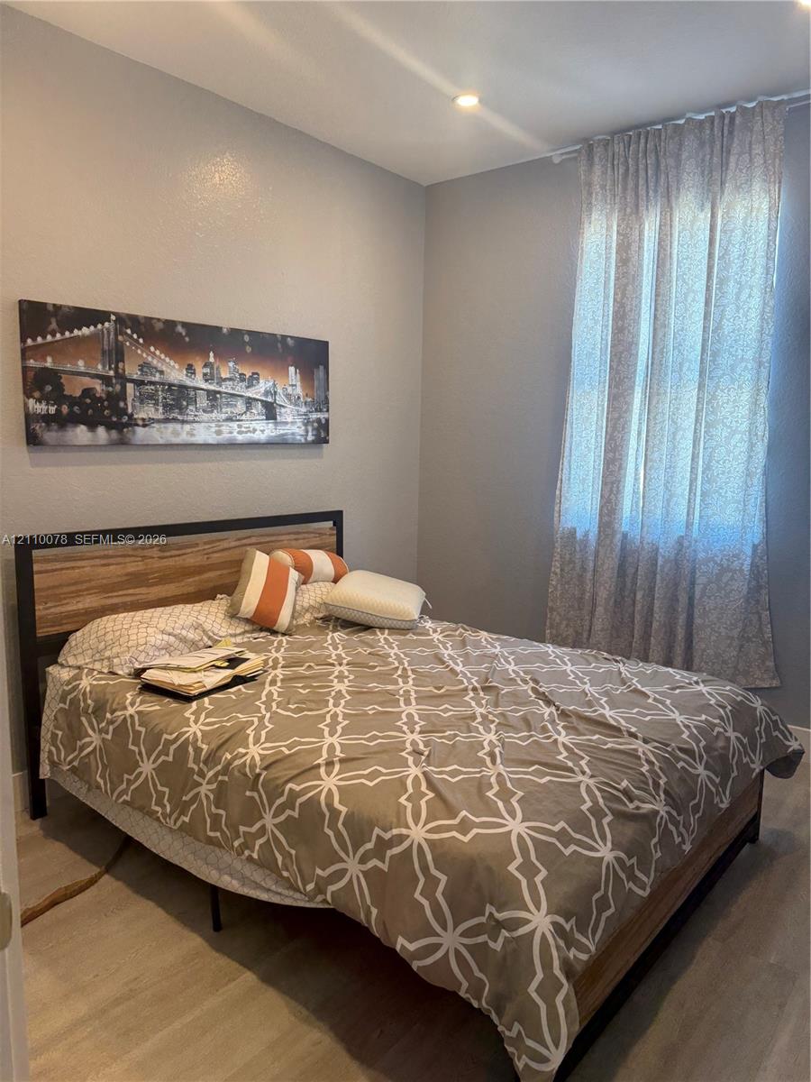 Room featuring light-toned wood-finish flooring, neutral wall paint, and floor-to-ceiling window drapery with recessed ceiling lighting