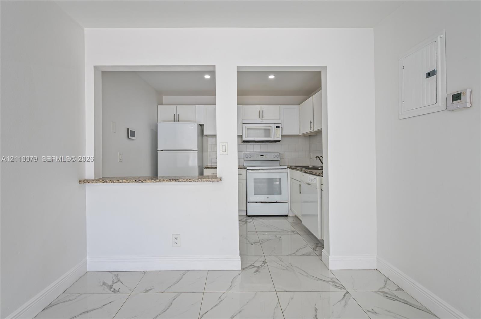 Kitchen featuring white cabinetry, stone-finish countertops, tile flooring, and integrated white appliances Kitchen featuring white cabinetry, stone-finish countertops, tile flooring, and integrated white appliances