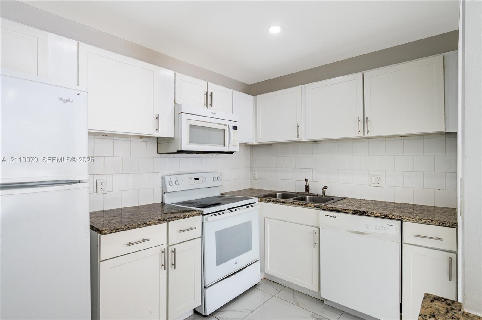 Kitchen featuring white cabinetry, stone-finish countertops, subway tile backsplash, white appliances, and tiled flooring Kitchen featuring white cabinetry, stone-finish countertops, subway tile backsplash, white appliances, and tiled flooring