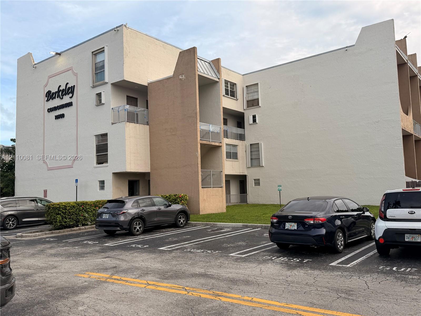 Multi-story stucco exterior featuring private recessed balconies with metal railings and dedicated surface parking