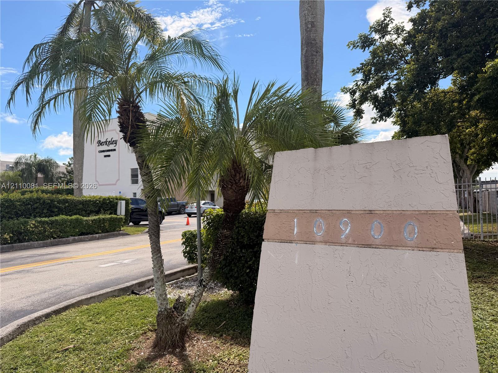 Stucco monument sign featuring address numbers and integrated palm tree landscaping