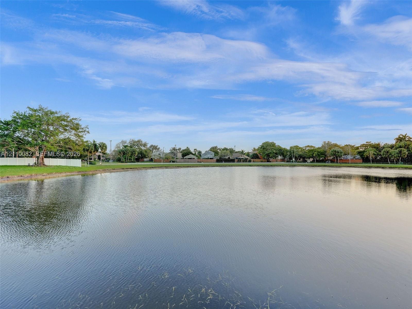 Waterfront lot featuring a wide expanse of open water, manicured grass perimeter, and mature trees