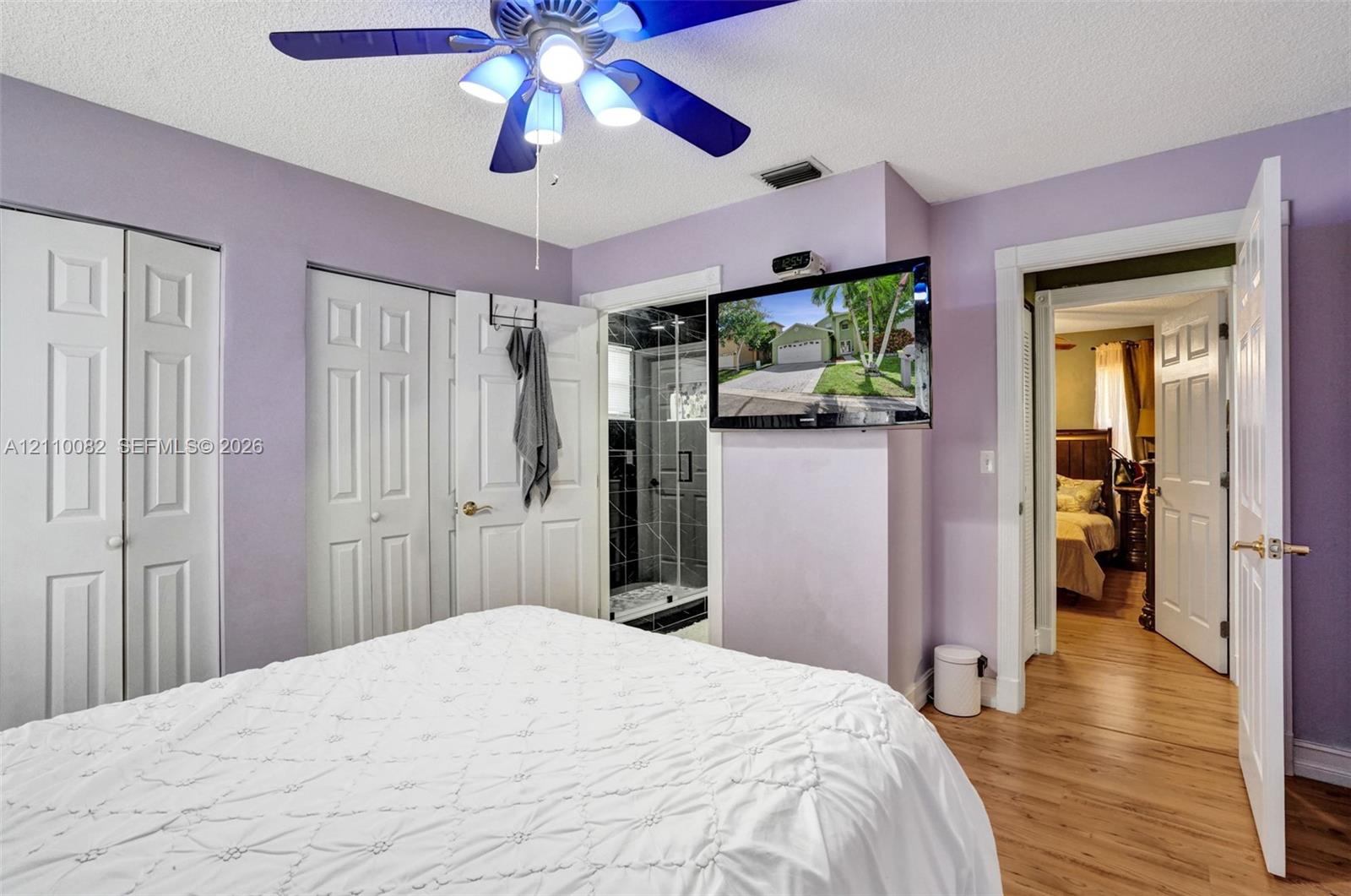 Bedroom featuring wood-finish flooring, dual-door closets, and a ceiling fan with integrated lighting