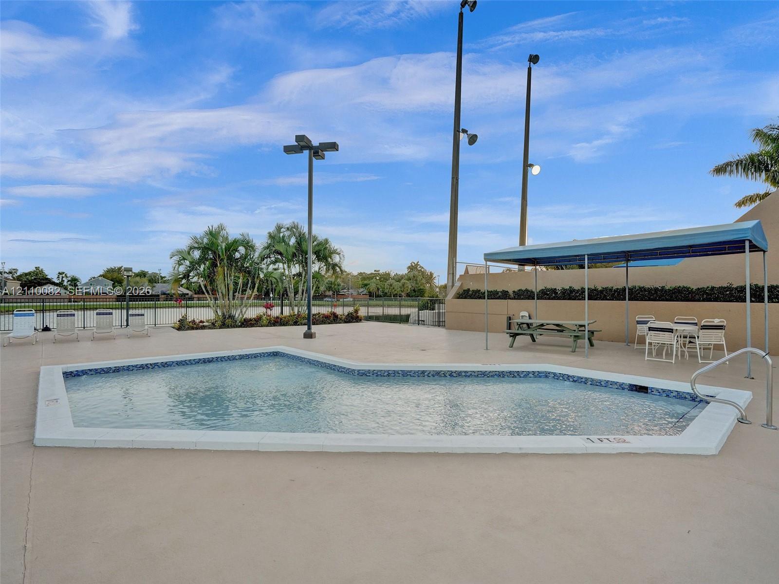 Pool area with concrete decking, a built-in metal canopy, and perimeter metal fencing