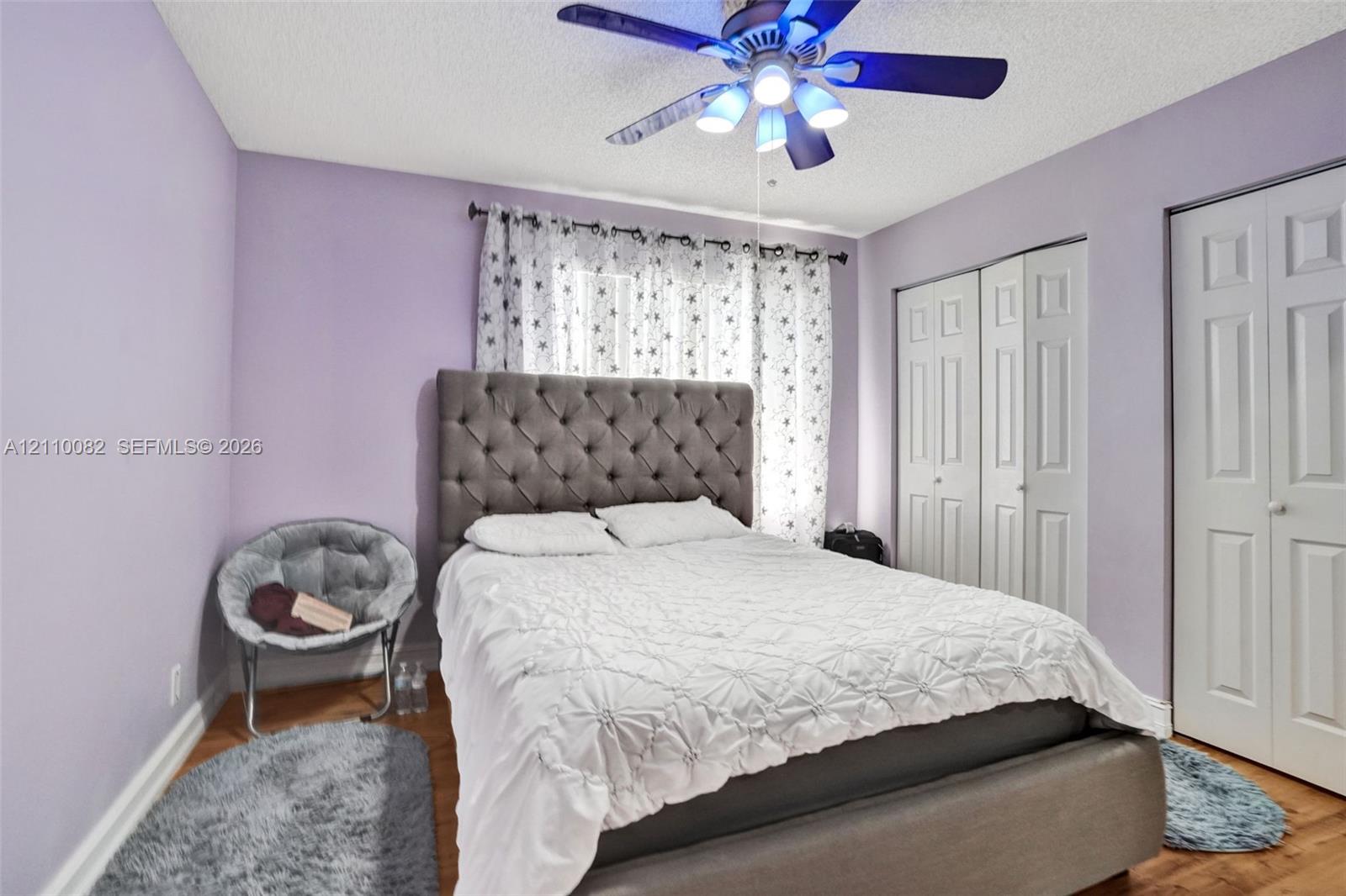 Wood-finish flooring, ceiling fan with integrated lighting, and dual-panel closet doors
