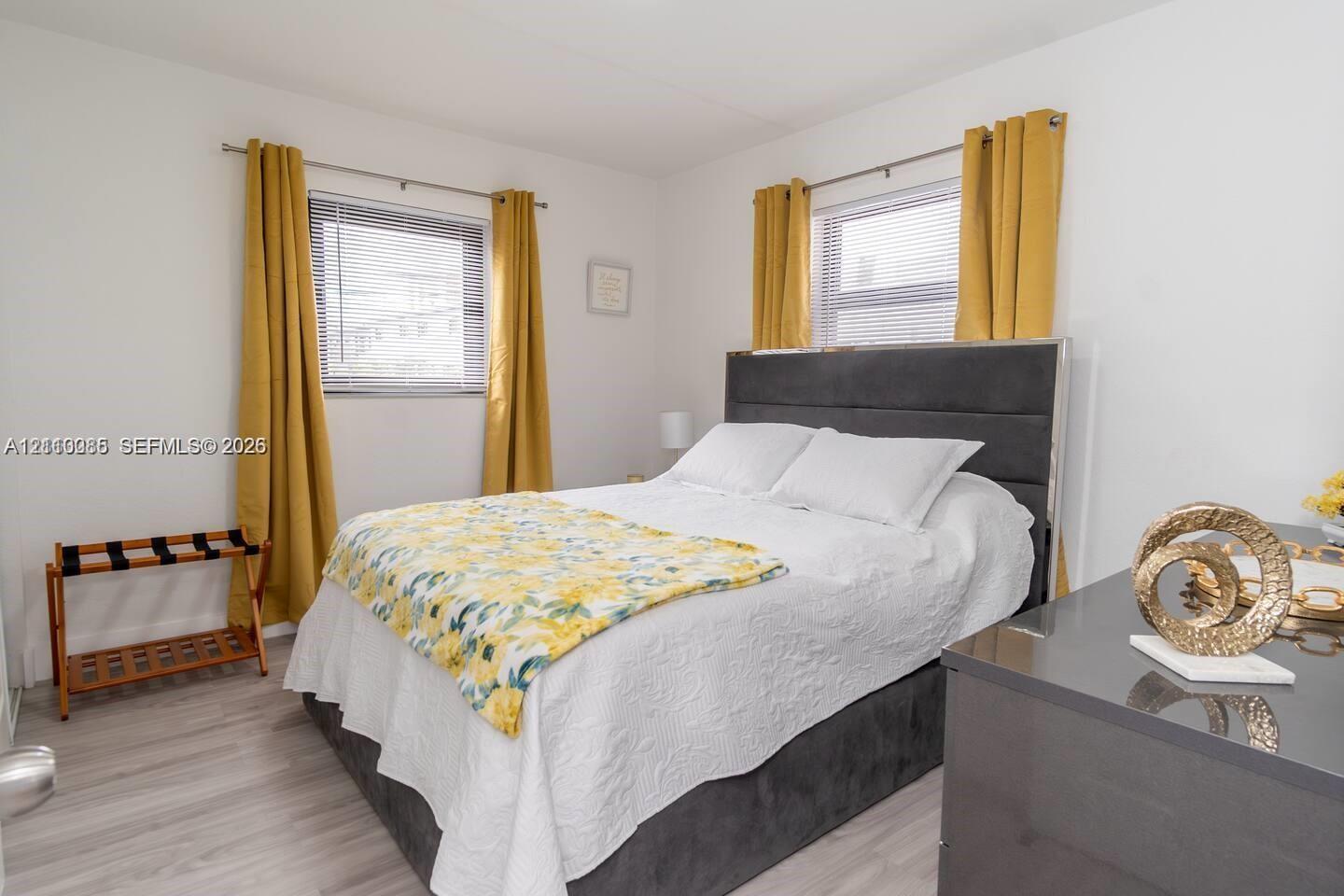 Room featuring wood-finish flooring, dual windows with horizontal blinds, and neutral wall tones