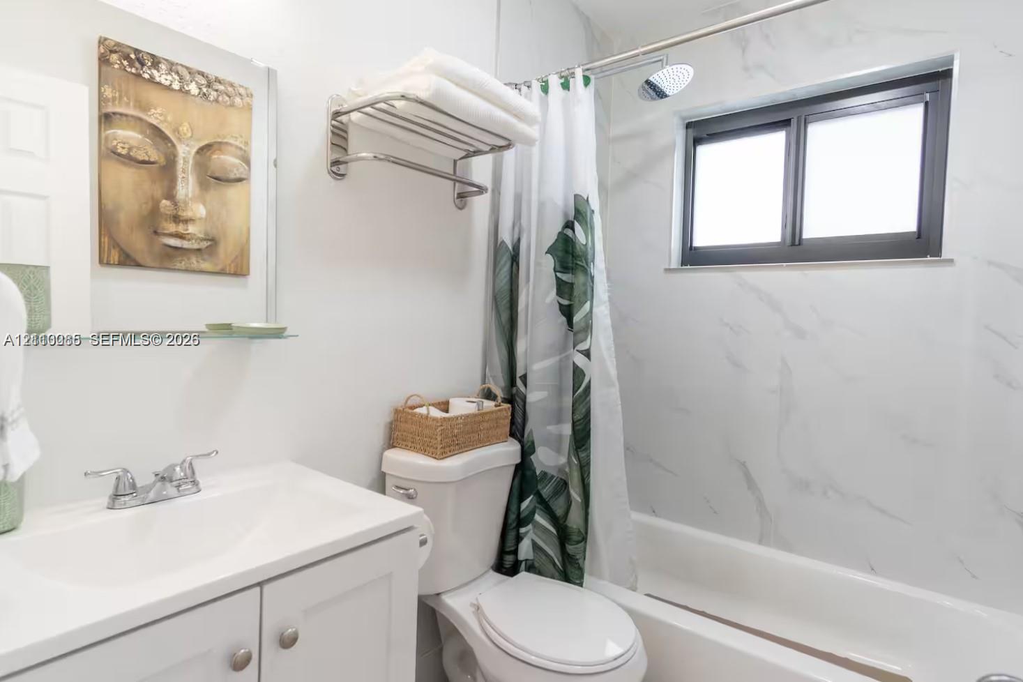 Bathroom featuring white vanity cabinetry, integrated sink, polished chrome faucet, wall-mounted towel rack, and tub-shower combination with light-toned wall tile