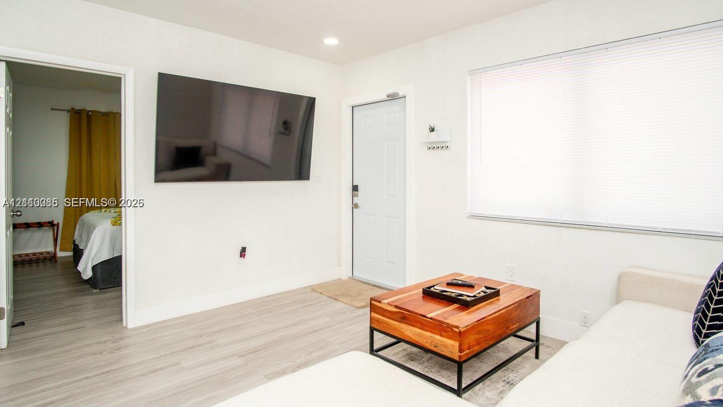 Interior featuring neutral wall tones, wood-finish flooring, recessed lighting, and a large horizontal window with fitted blinds