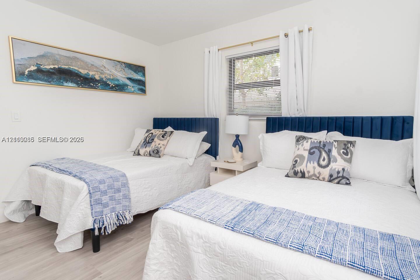 Neutral-toned room featuring wood-finish flooring and a window with horizontal blinds