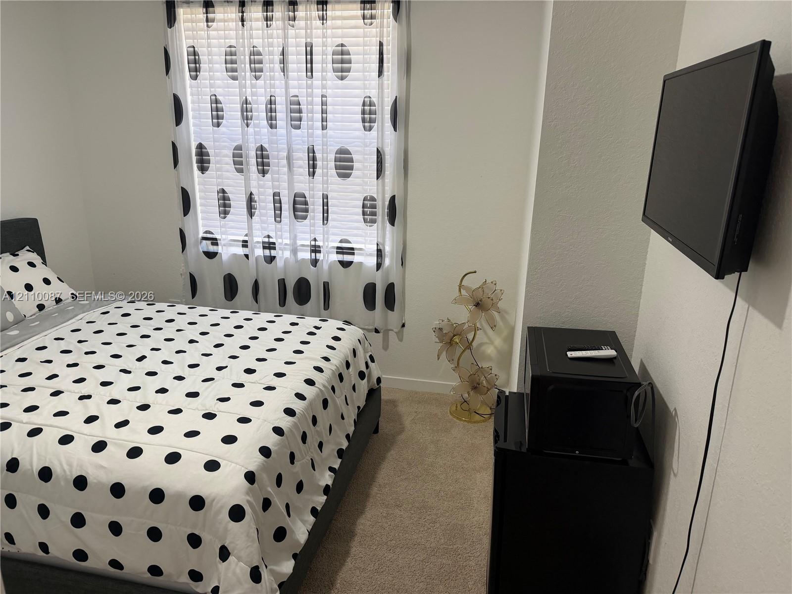 Neutral-toned carpeted flooring, white wall finish, and a window with horizontal blinds