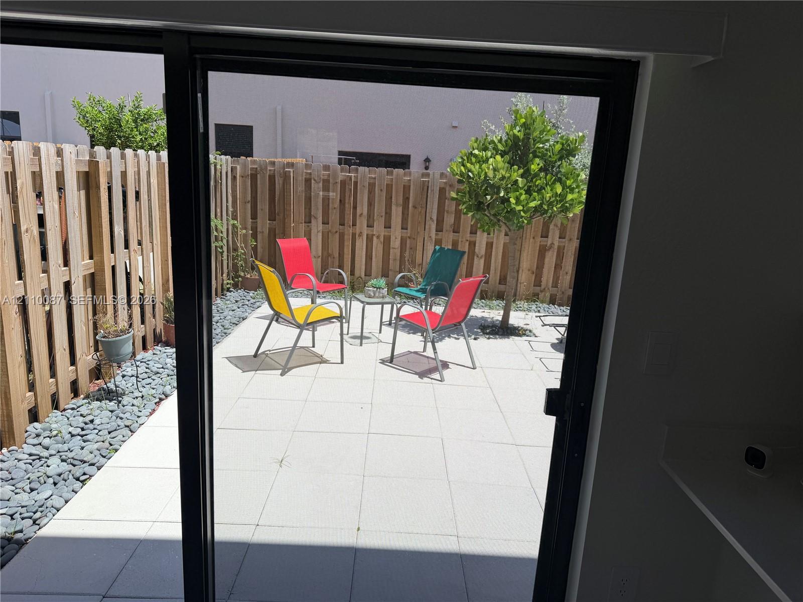 Private outdoor patio featuring light-toned concrete pavers, stone gravel borders, and a vertical wood-plank privacy fence