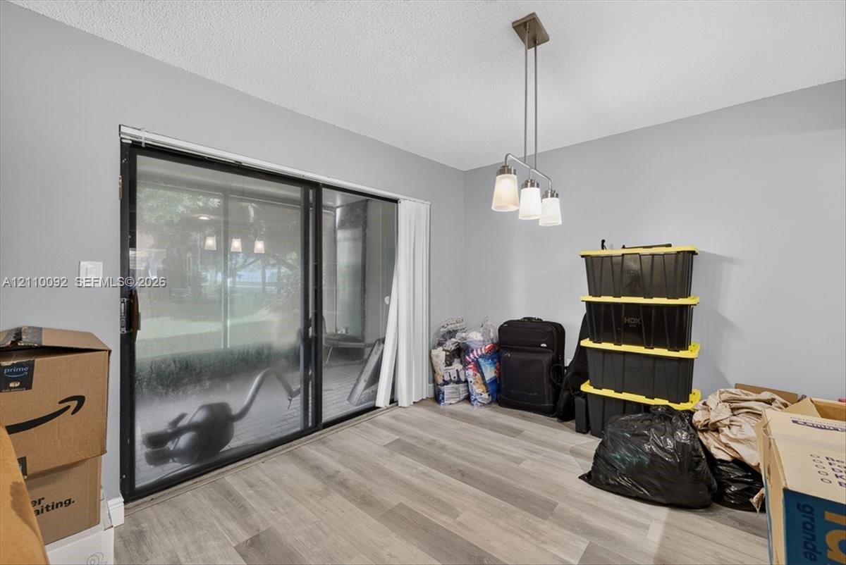Sliding glass door leading to a screened enclosure, wood-finish flooring, and a three-light pendant fixture